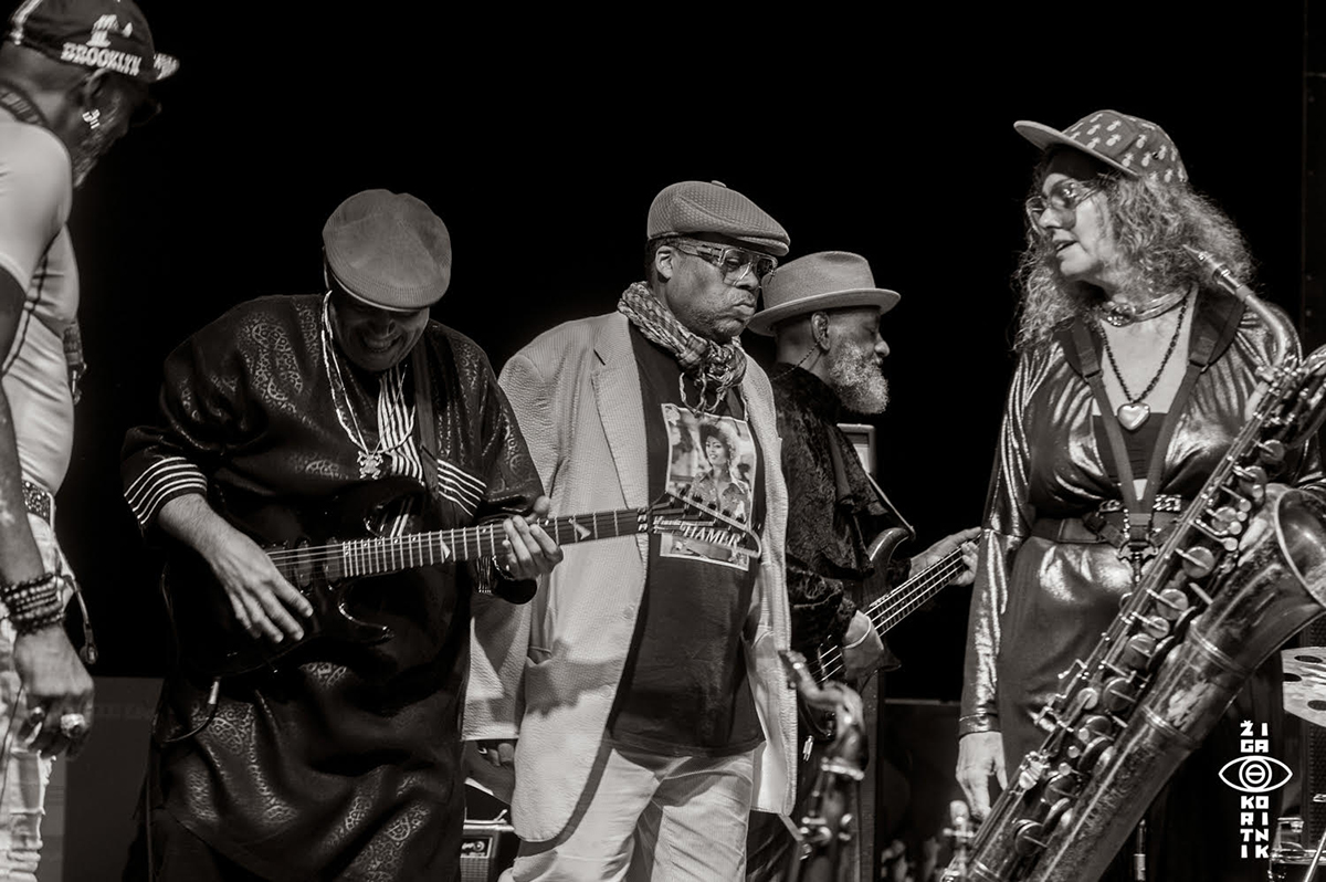 Black and white photo of five musicians, including Greg Tate, making music.